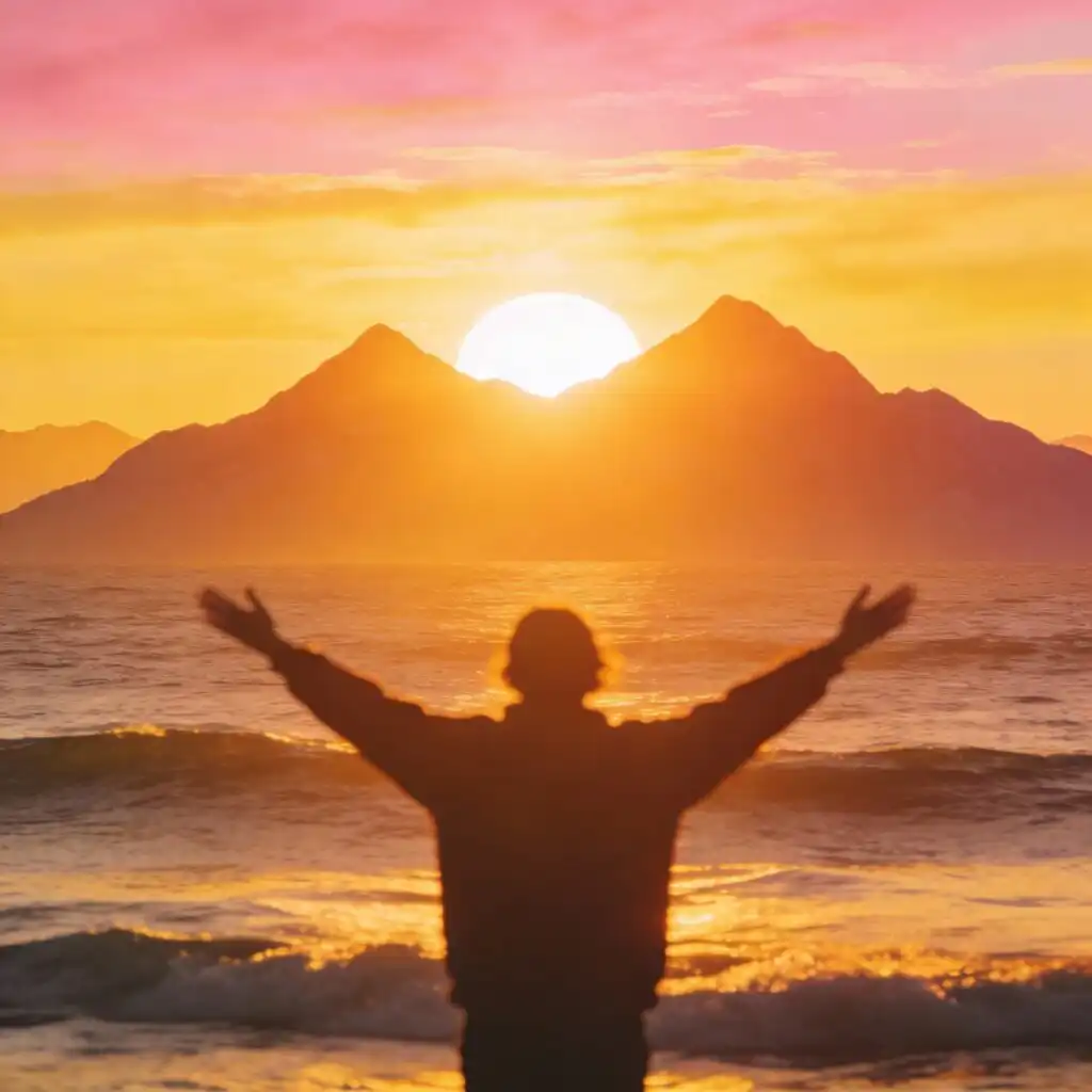 Person standing at sunrise with arms open toward new hopeful future ahead