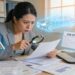 Woman examining financial documents and bank statements with magnifying glass to uncover hidden assets during divorce proceedings